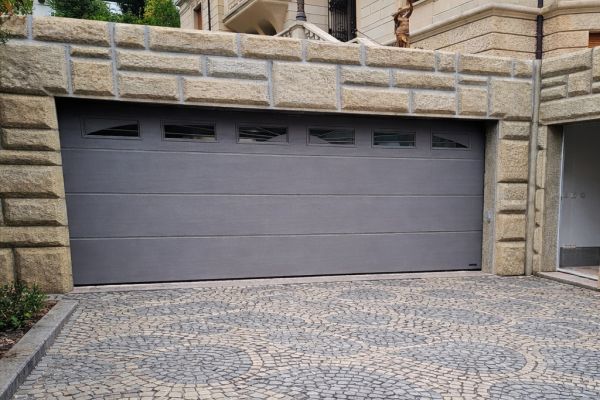 Garagentor in Wiesbaden in RAL 9007 Aluminiumgrau vor Natursteinfassade UniPro Garagen-Sektionaltor mit Designfenstern im oberen Paneel, Wiesbaden Detailansicht der Woodgrain-Oberfläche am Garagentor