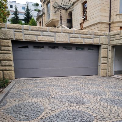 Garagentor in Wiesbaden in RAL 9007 Aluminiumgrau vor Natursteinfassade UniPro Garagen-Sektionaltor mit Designfenstern im oberen Paneel, Wiesbaden Detailansicht der Woodgrain-Oberfläche am Garagentor